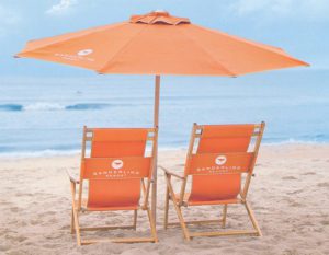 two orange lounge chairs and an umbrella at the beach