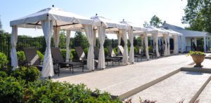 a row of white gazebo tents and lounge chairs