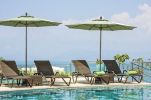 four lounge chairs and two umbrellas by the pool