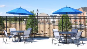 two sets of outdoor chairs and tables with blue umbrellas