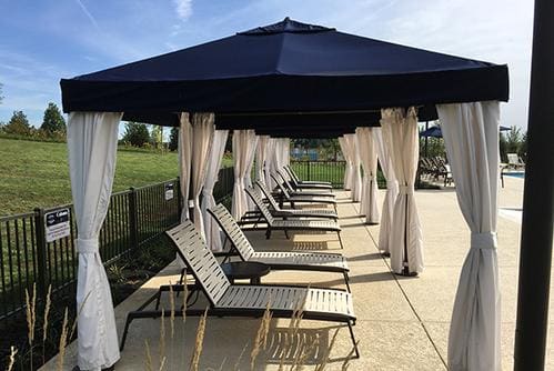 A row of lounge chairs under an umbrella.