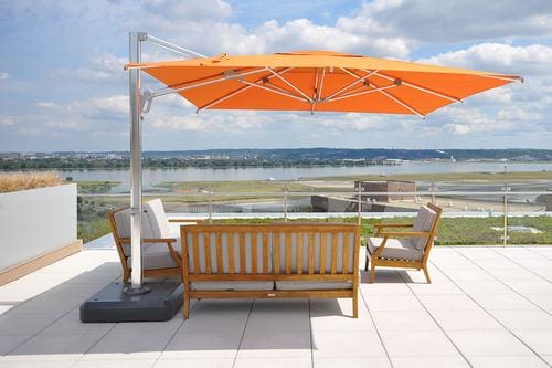 A patio with an umbrella and chairs on the ground.