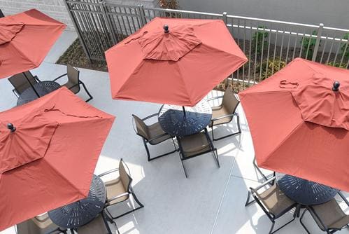 A group of people sitting at tables with umbrellas.