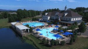 A large pool with many blue umbrellas and people in it.
