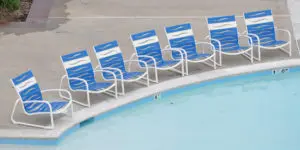 a row of blue chairs on the side of a pool
